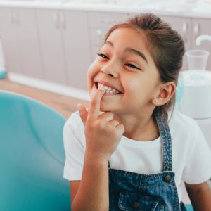 Mixed race little patient showing her perfect toothy smile while sitting dentists chair Mixed race little patient showing her perfect toothy smile while sitting dentists chair