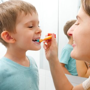 Young caring mother brushing and cleaning teeth of her little son. Parents and children taking care of teeth health and hygiene Young caring mother brushing and cleaning teeth of her little son. Parents and children taking care of teeth health and hygiene.